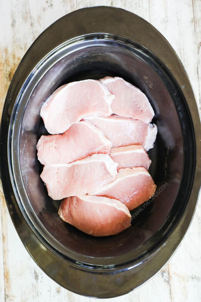 How to make crockpot smothered pork chops step 1: lay boneless pork chops in the crockpot and season.