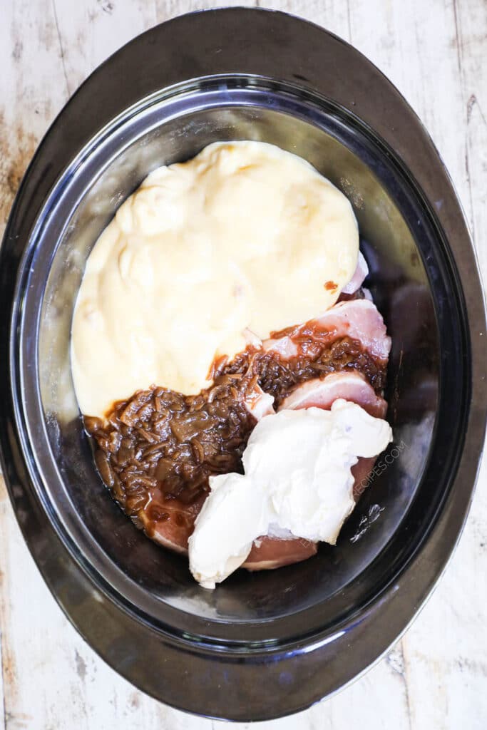 How to make crockpot smothered pork chops step 2: add cream of chicken soup, french onion soup, and sour cream.