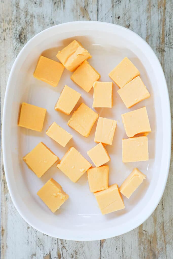 How to make Queso chicken step 1: cube velveeta cheese and place in the casserole dish.