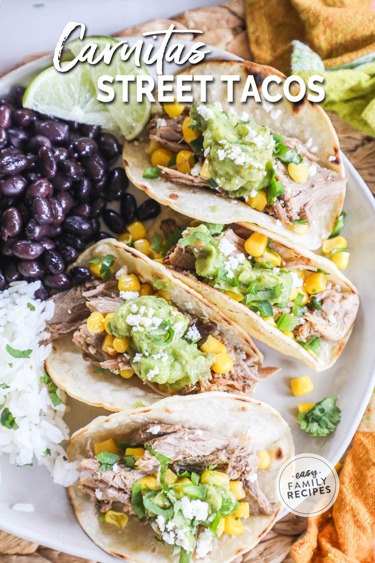 Four tacos with a side of black beans and rice on a large white plate.