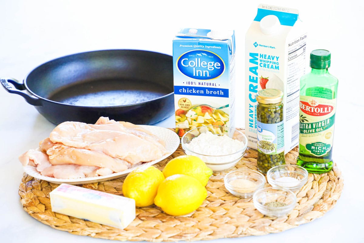 Ingredients for making creamy chicken piccata including chicken breast, lemon, butter and cream.