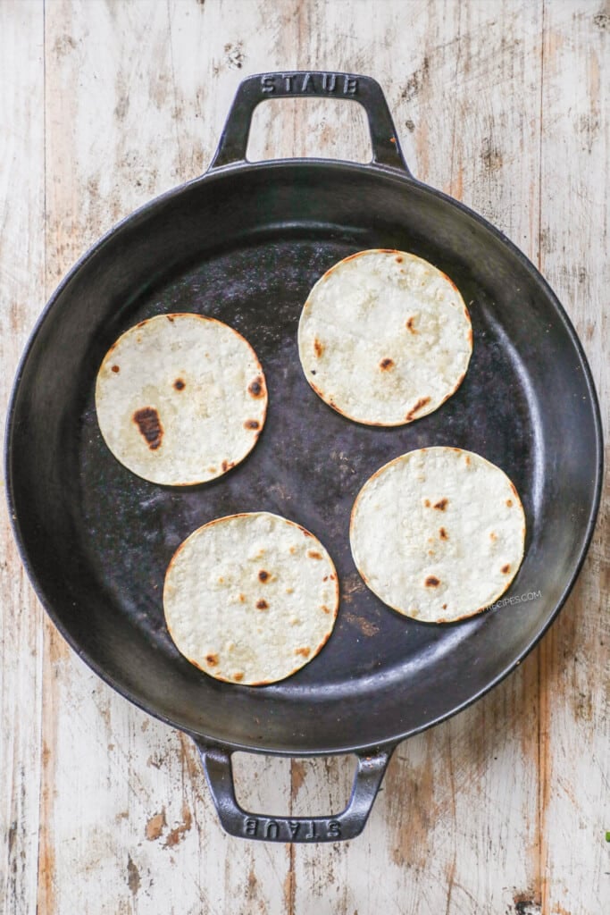 How to Make pork carnitas street tacos step 1: lightly toast corn tortillas in a skillet.