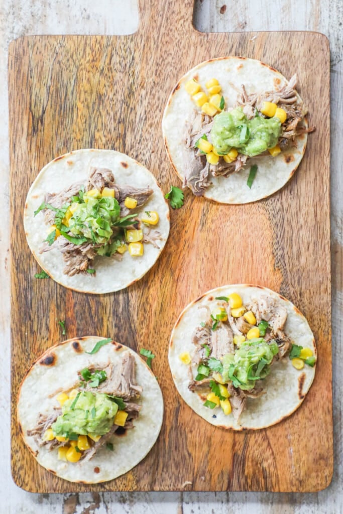 How to Make pork carnitas street tacos step 3: Top carnitas taco with your choice of toppings including corn, guacamole, cheese, and salsa.