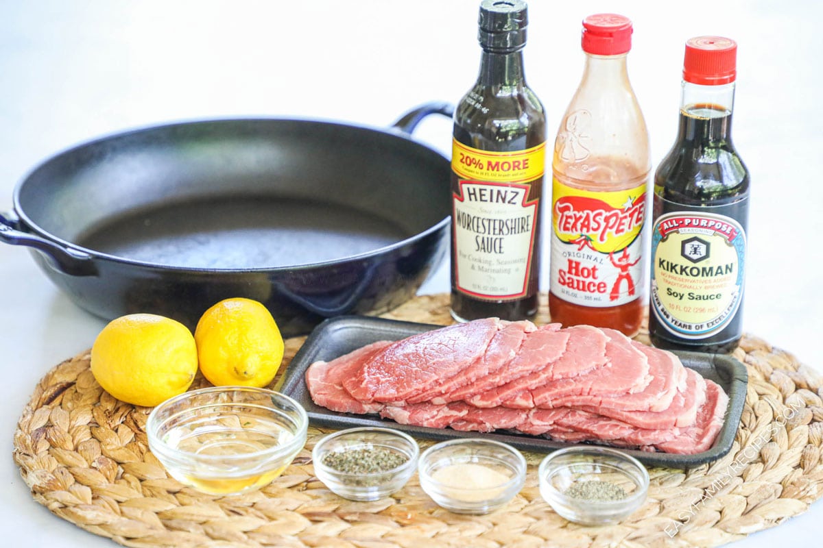 Ingredients for sizzle steak including thinly sliced beef, lemon, spices, Worcestershire, soy sauce, and hot sauce