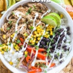 Ove head view of white bowl with pork carnitas, rice, black beans, corn limes, and red pepper. Drizzled with sour cream