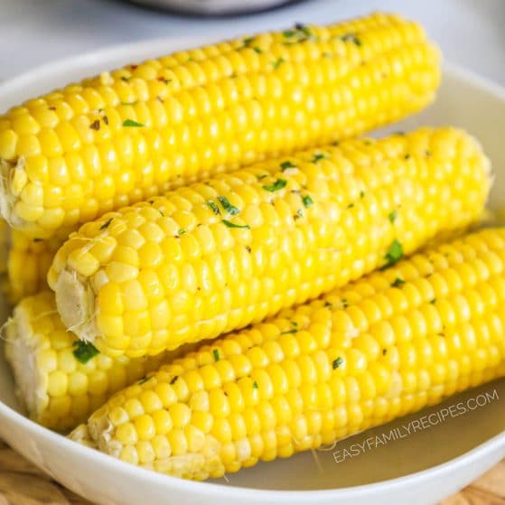 Close up of garlic herb butter corn cobs in serving dish.