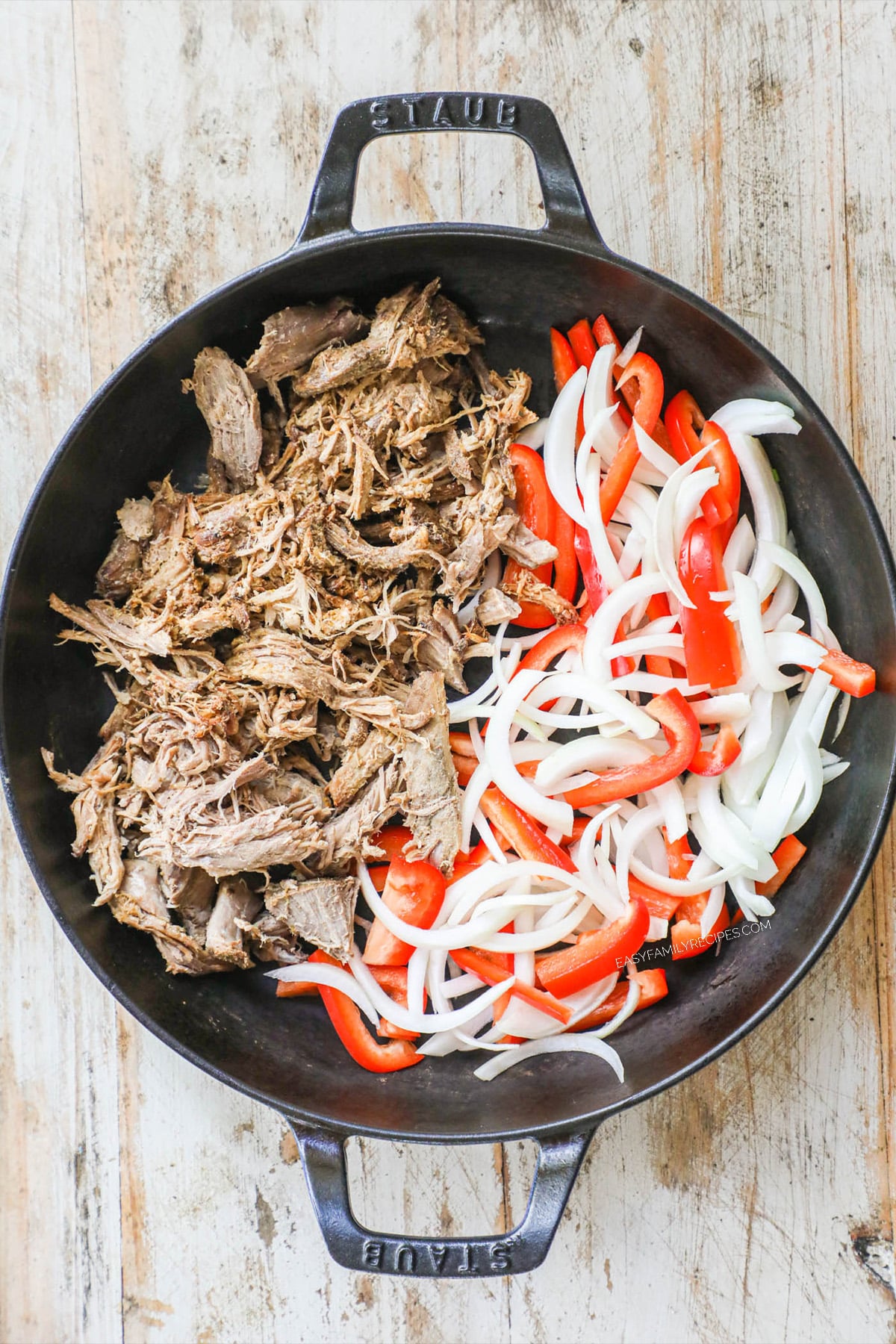 Step ! of burrito bowl recipe - a skillet with pork carnitas, peppers and onions