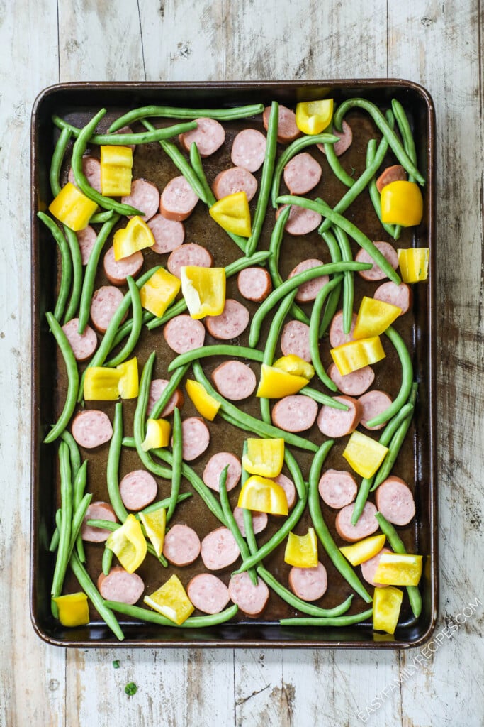 How to make cajun sausage sheet pan dinner step 2: Add bell peppers, green beans and diced potatoes.