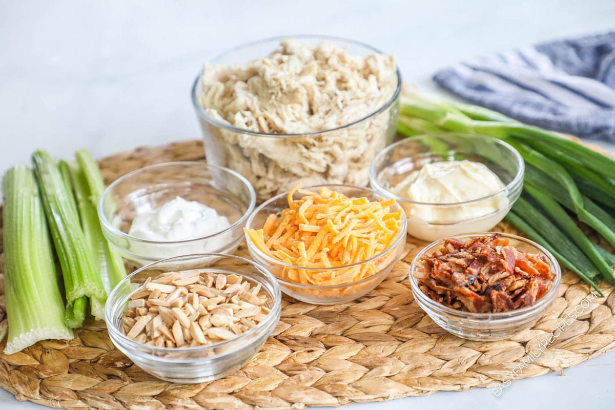 Ingredients to make this chicken salad including shredded chicken, green onions, mayo, sour cream, bacon bites, and cheddar cheese.
