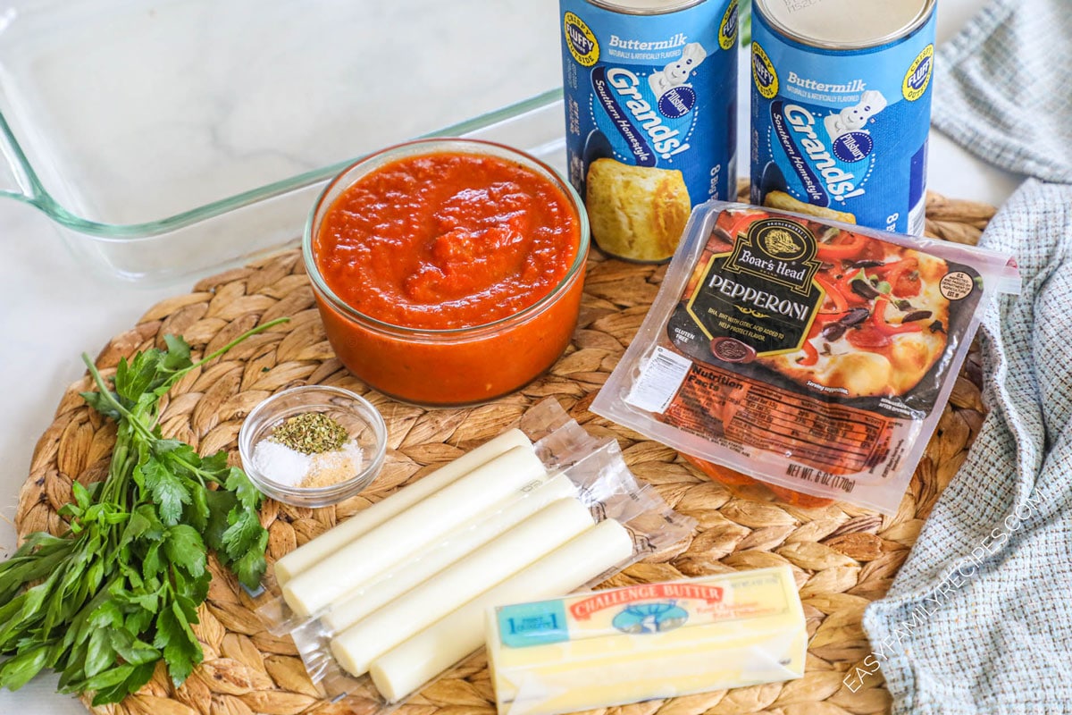 Ingredients for recipe: fresh herbs, seasonings, marinara, individually wrapped mozzarella sticks, stick of butter, pack of pepperoni, and 2 containers of grands biscuits.