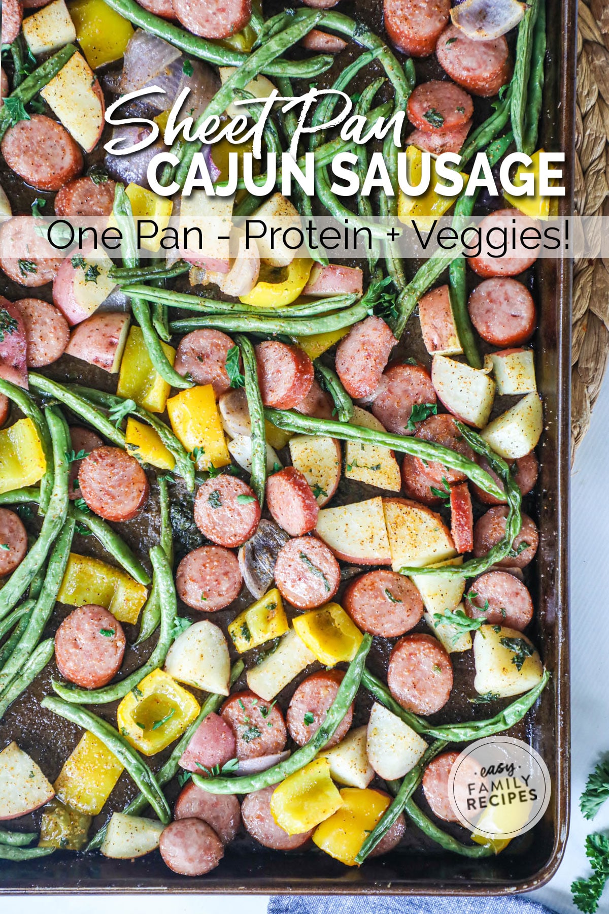 Sheet pan with sausage, green beans, and potatoes on it.