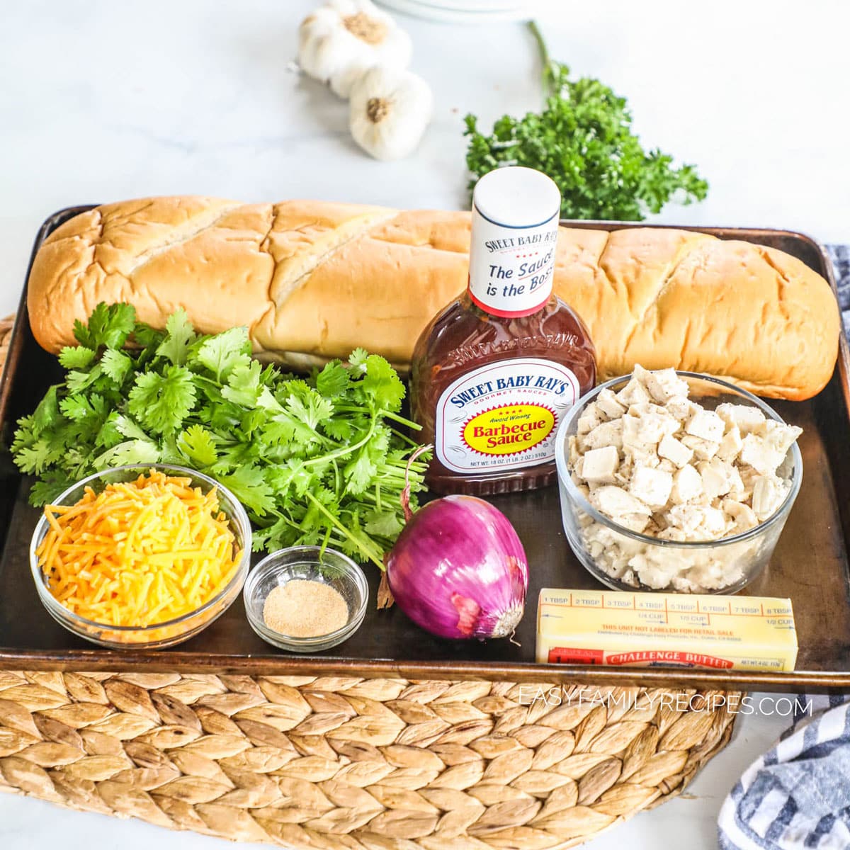 Ingredients for bbq chicken pizza including french bread, bbq sauce, chicken, cilantro, cheddar cheese, garlic salt, butter, and red onion.