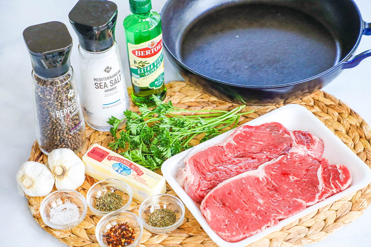 Ingredients for garlic herb steak including steak, garlic, olive oil, butter, salt, pepper, herbs, and red pepper flakes.
