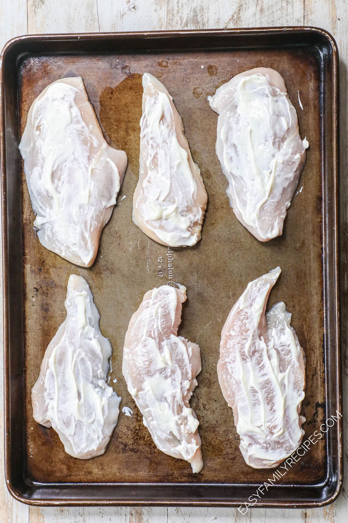 uncooked chicken breasts on a pan