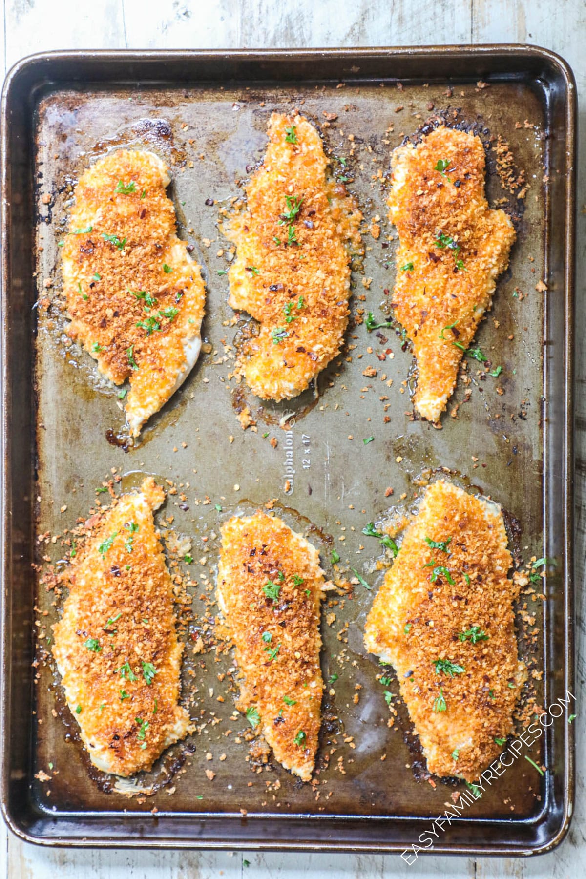 cooked and breaded chicken breast on cookie sheet