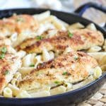a pan of creamy pasta topped with crispy, breaded chicken cutlets.