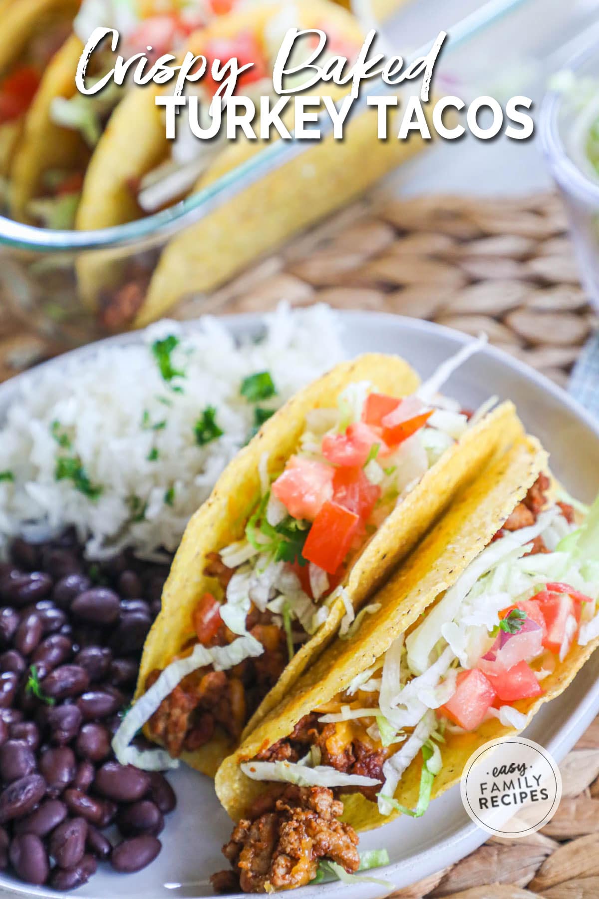 Close up image of ground turkey tacos with lettuce and tomatoes on top and black beans on a plate beside the tacos.