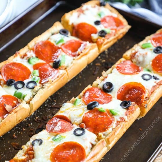 Garlic bread pizza with supreme toppings on a sheet tray.