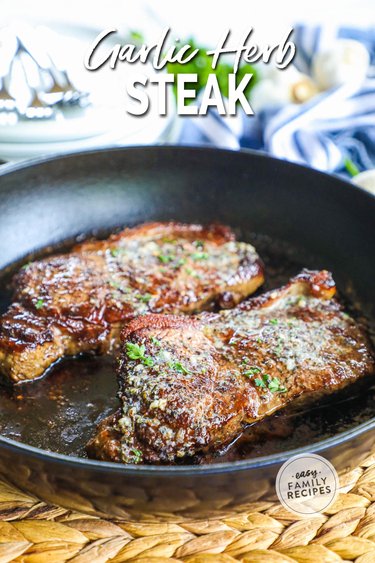 Two pieces of seared steak in a cast iron skillet with green herbs on top.