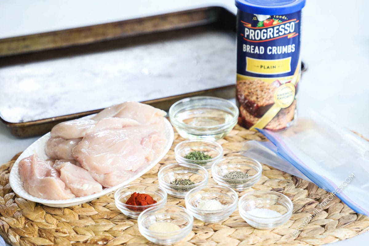 Ingredients to make homemade shake and bake including chicken, spices, herbs, salt, oil, and breadcrumbs.