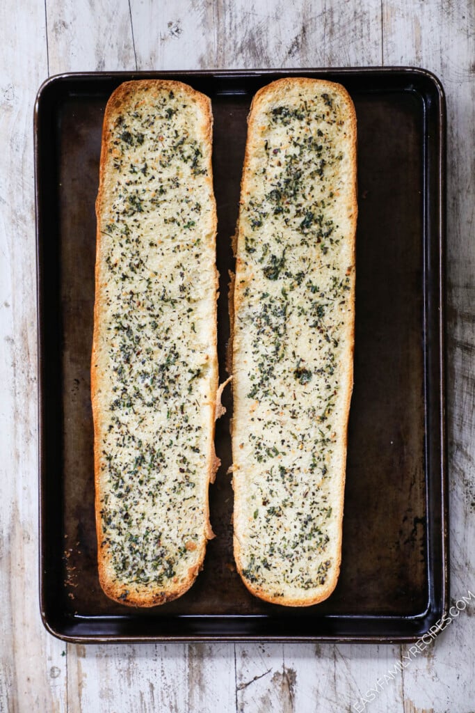 How to make garlic bread pizza step 1: Cut french bread in half and add butter and seasonings.
