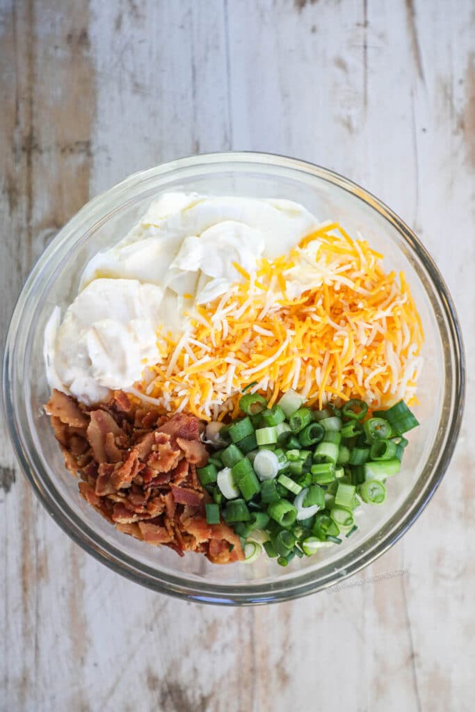 How to make Million Dollar Chicken Step 1: Add mayonnaise, sour cream, shredded cheese, green onions, and bacon to a bowl.