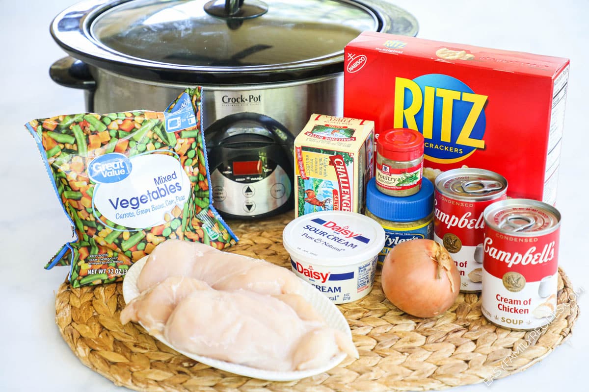 Ingredients to make slow cooker chicken pot pie including chicken breasts, ritz crackers, condensed soup, and mixed vegetables.