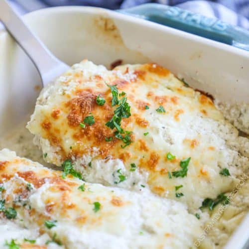 A spatula taking sour cream chicken breast out of a pan.