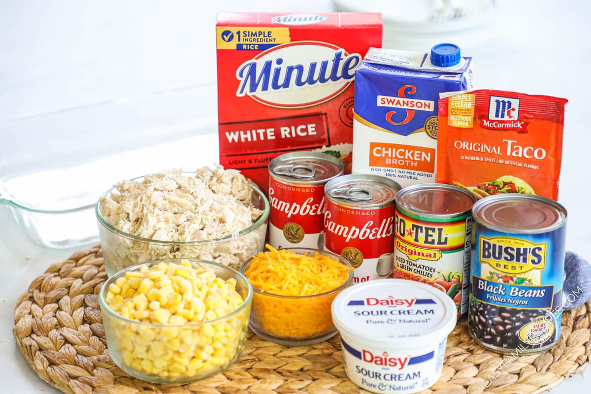 Ingredients for chicken burrito casserole including chicken, cheese, cream of chicken soup, instant rice, black beans, corn, rotels salsa, chicken broth, taco seasoning, and sour cream.