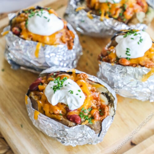 Baked potatoes stuffed with chili and toppings and wrapped in foil