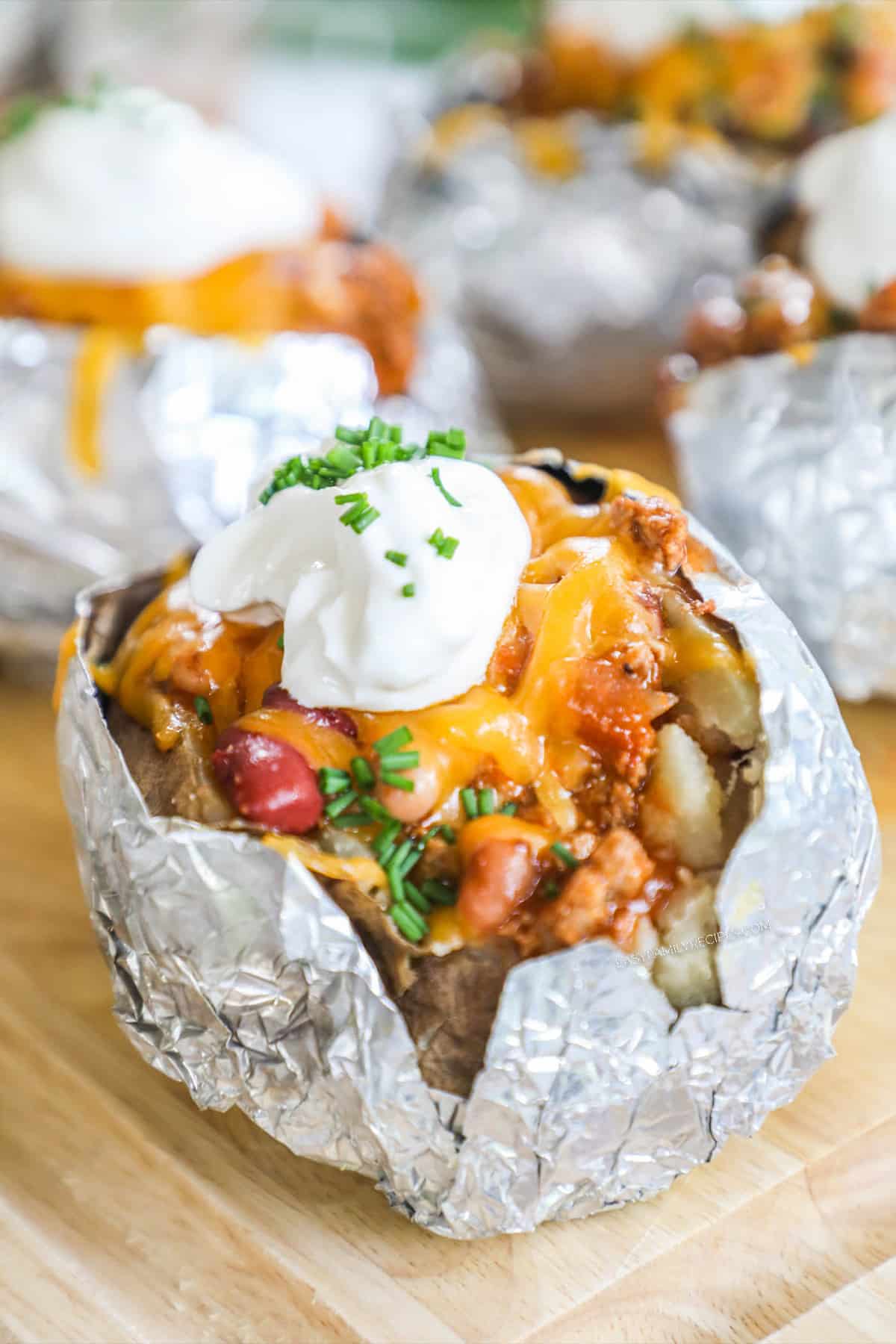 Baked potatoes stuffed with chili and toppings and wrapped in foil