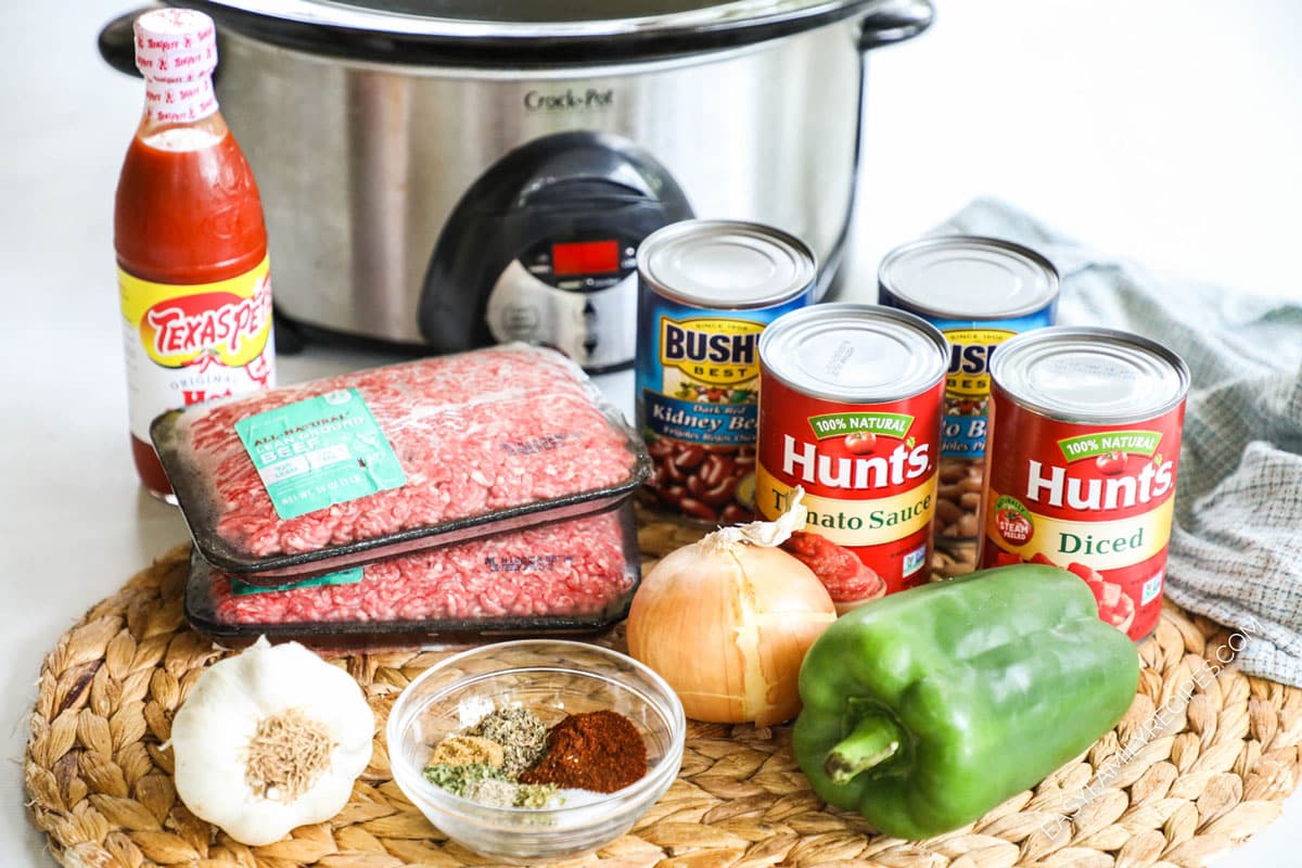Ingredients to make Crock Pot beef chili including beans, tomato sauce, bell pepper, onion, and spices.