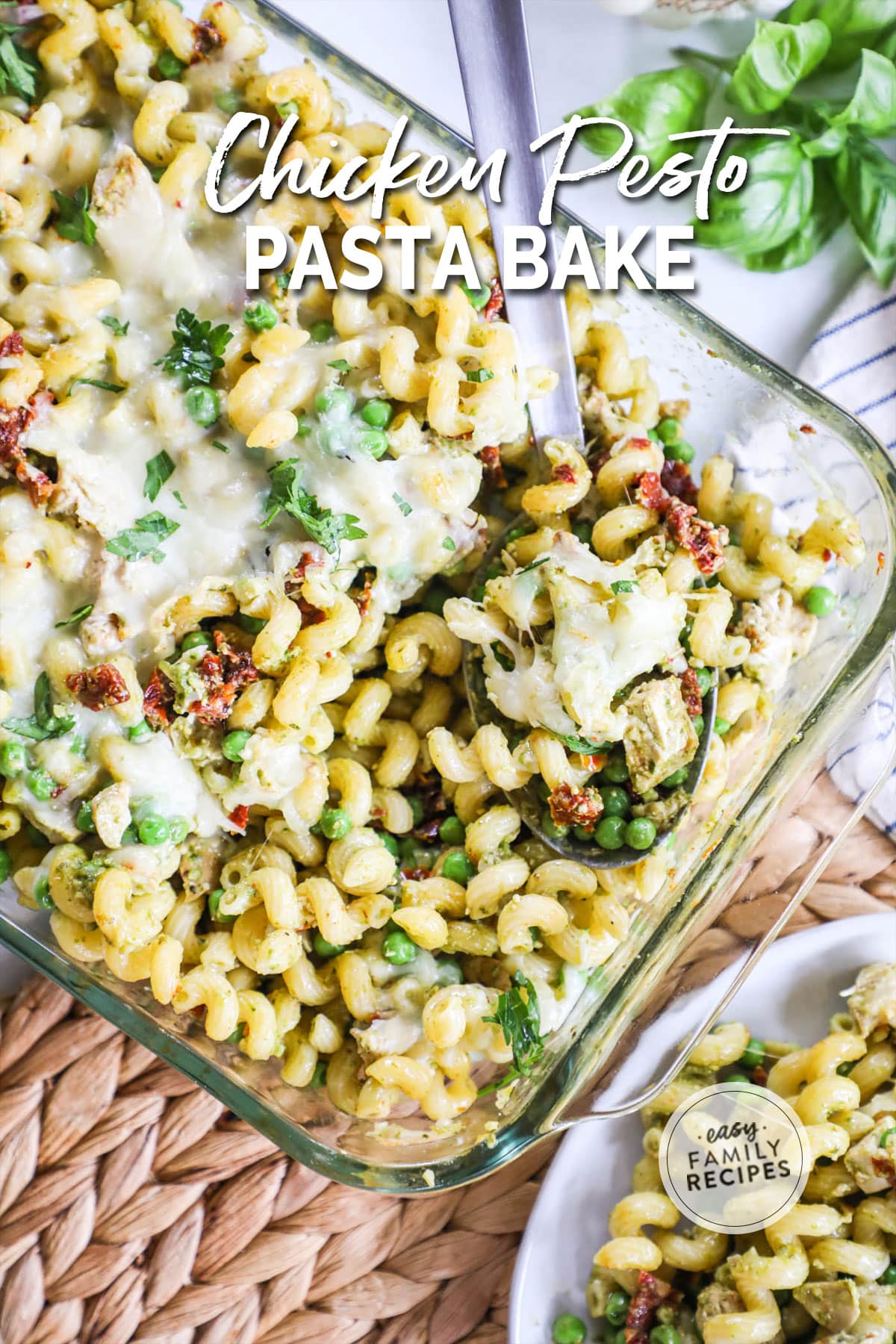 a chicken pesto past bake in a casserole dish with a spoon.