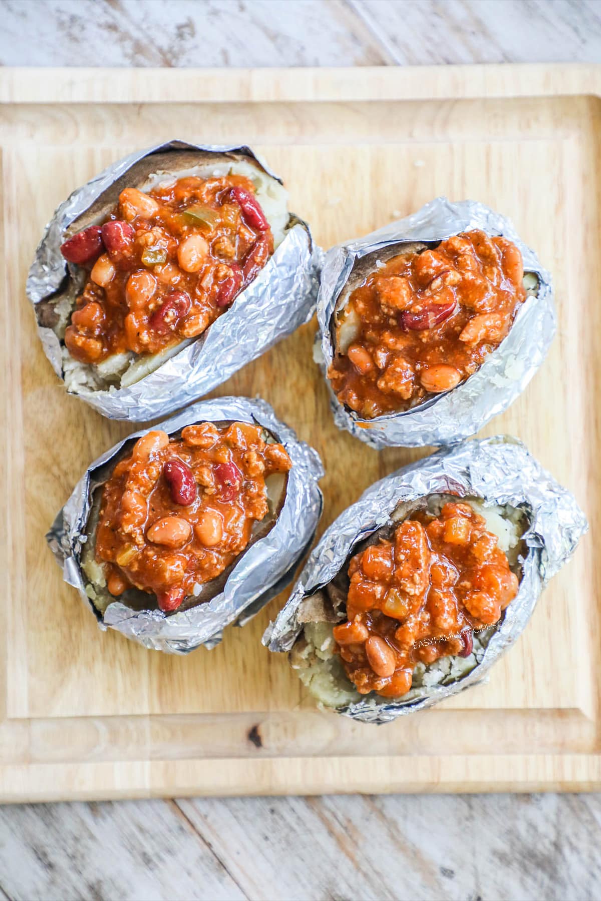 Step 2 of Stuffed Chili Baked Potatoes - Top each baked potato with chili and crumbled bacon