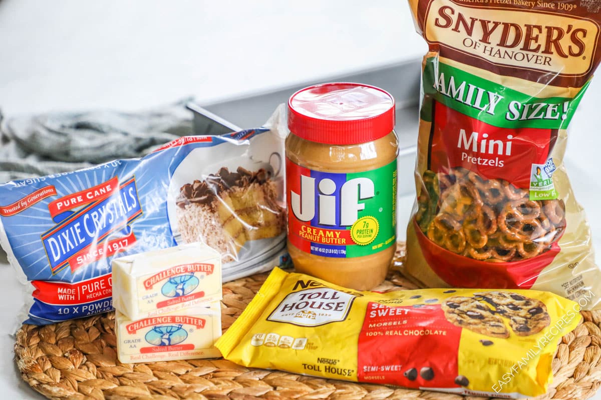 Ingredients for no bake bars including peanut butter, chocolate, pretzels, butter, and powdered sugar.