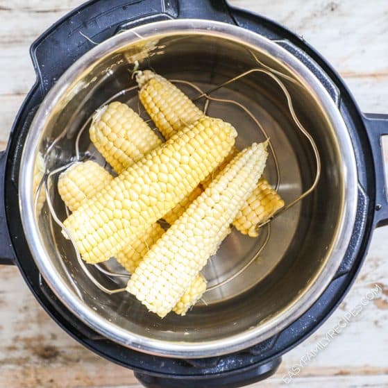 Corn on the cob piled into an Instant Pot on a trivet.