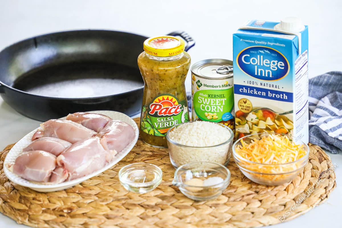 Ingredients to make salsa verde chicken and rice skillet including chicken thighs, corn, cheese, rice, and chicken broth.