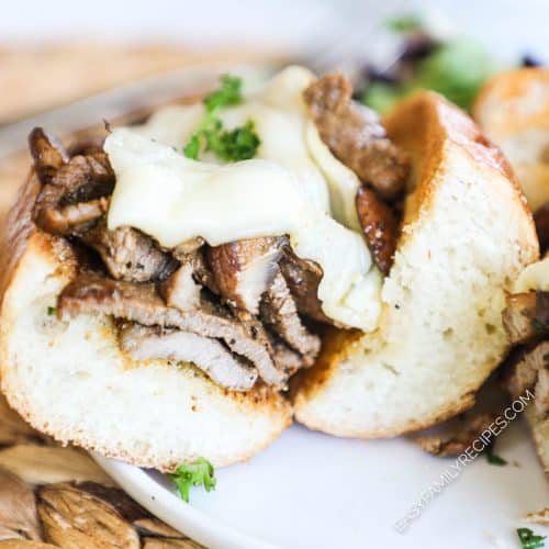 A cut open steak sandwich with charred steak and melted cheese.