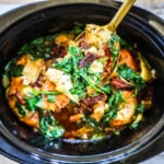 Tuscan Chicken being lifted from slow cooker.