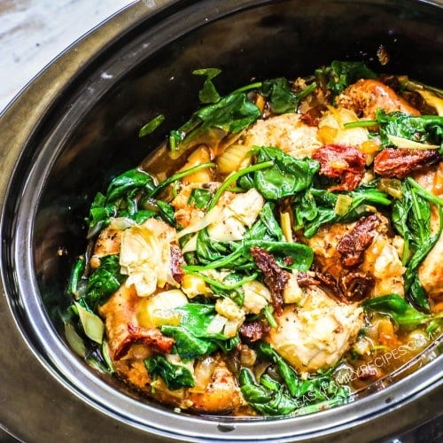 Crock Pot Tuscan Chicken recipe prepared in a slow cooker with shredded chicken, spinach, and sun-dried tomatoes vibrantly shown on the top of the dish