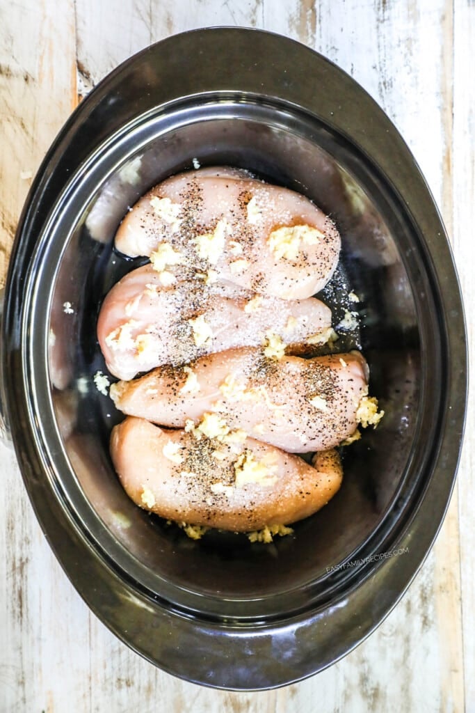 How to make slow cooker tuscan chicken step 1: Place chicken breast in crockpot with garlic and seasonings.
