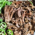 shredded beef barbacoa in a bowl with cilantro and jalapeno slices.