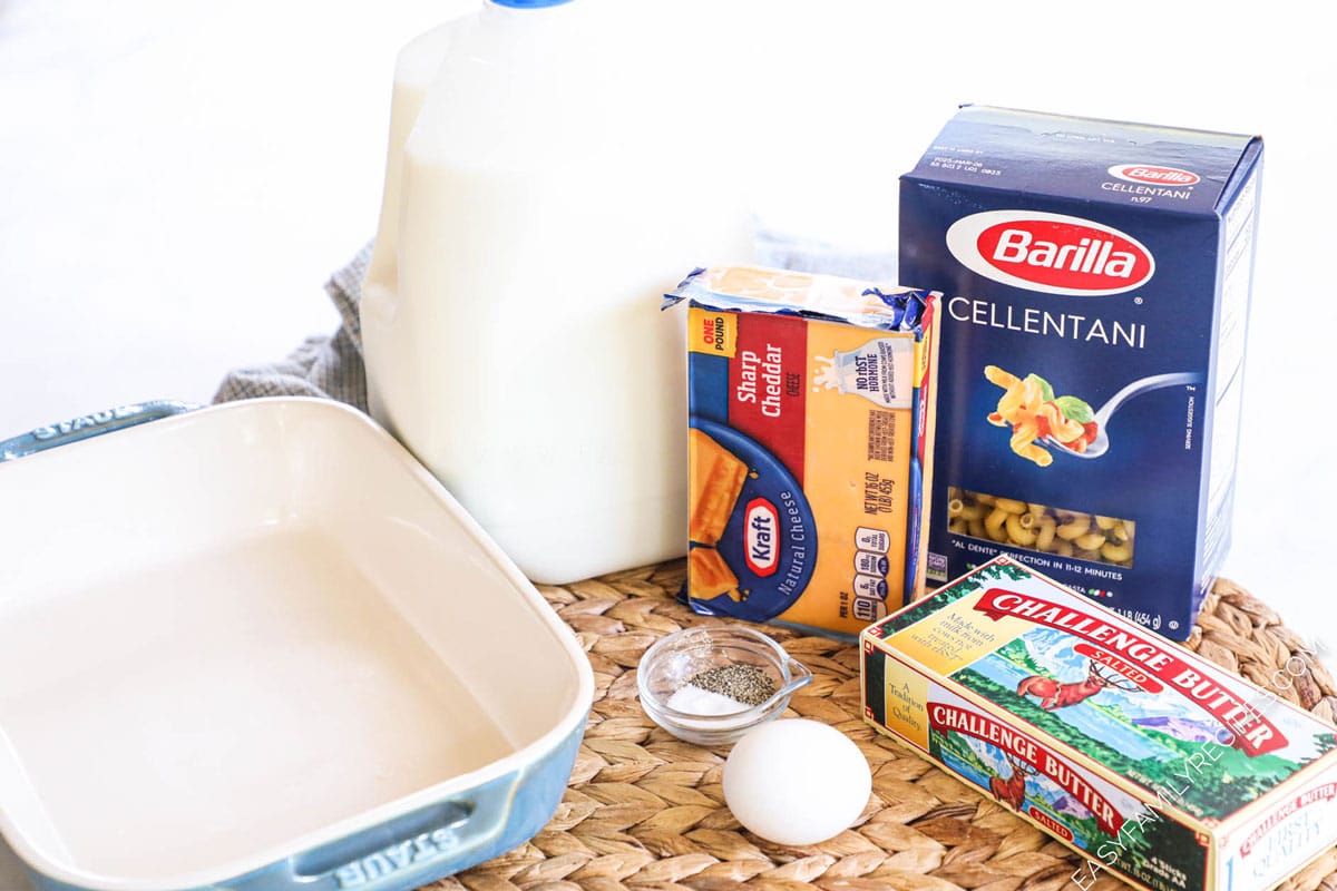 Ingredients for baked macaroni and cheese including pasta, milk, cheese, butter, egg, and salt and pepper.