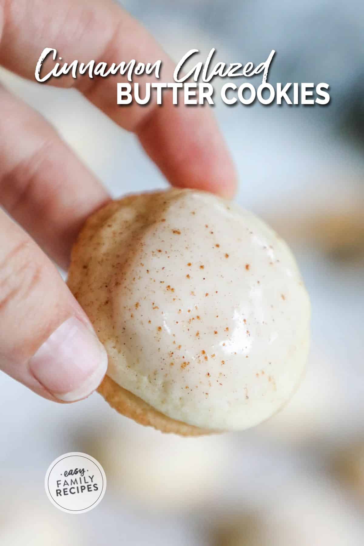 A hand holding a cinnamon dusted and glazed butter cookie.