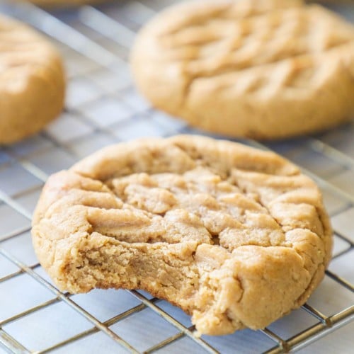 chewy peanut butter cookie sitting on a cooling rack with a bite taken out of it