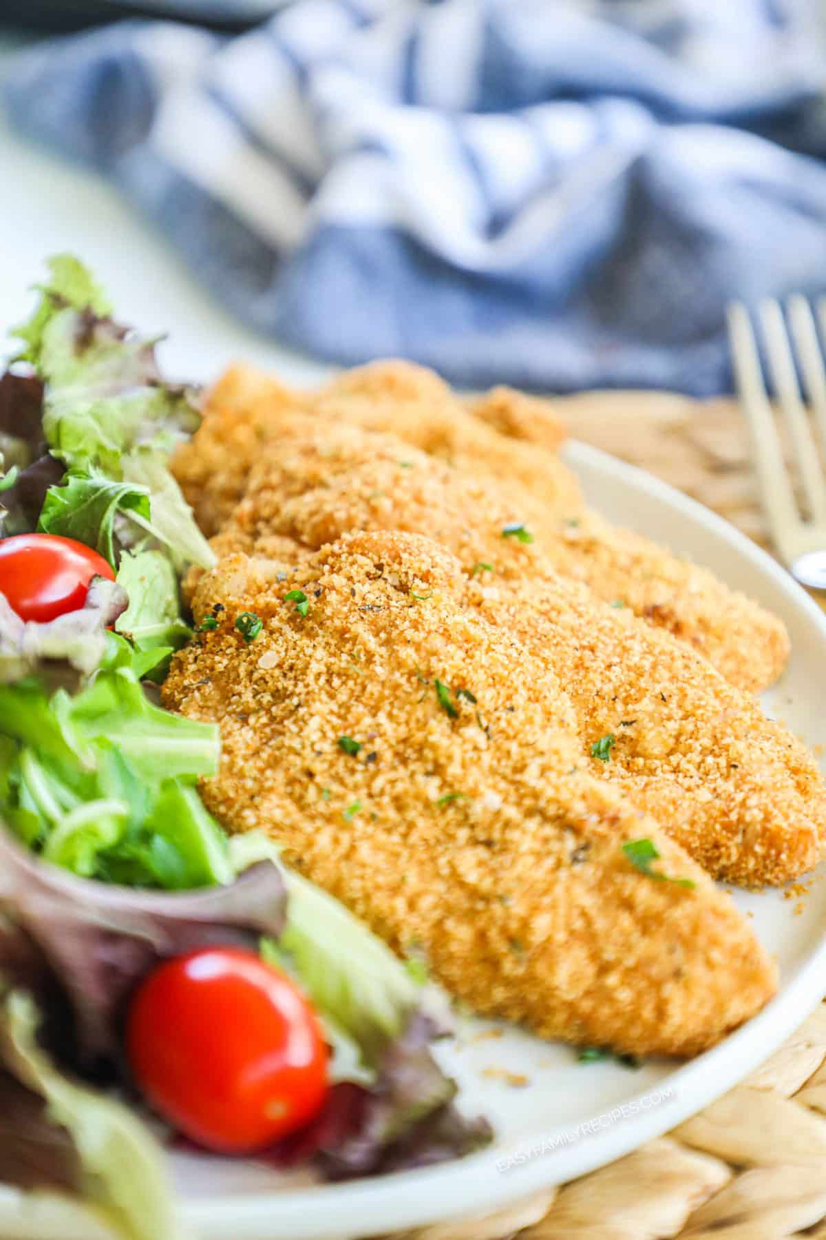 Plate with shake and bake breaded pork chops and salad on it.