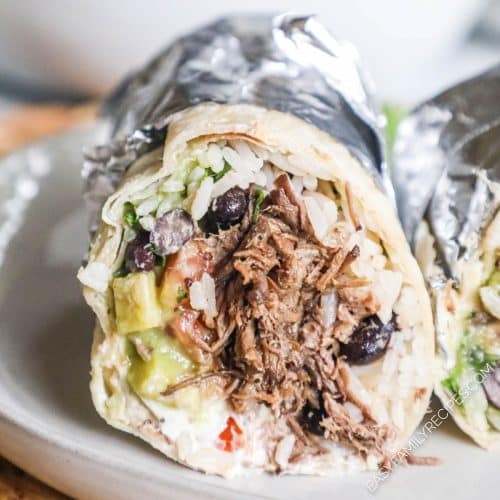 A completed burrito cut open to show all the fillings and wrapped in foil.