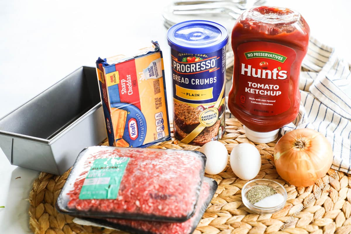 ingredients to make a cheeseburger stuffed meatloaf including breadcrumbs, ketchup, onion, eggs, and beef.