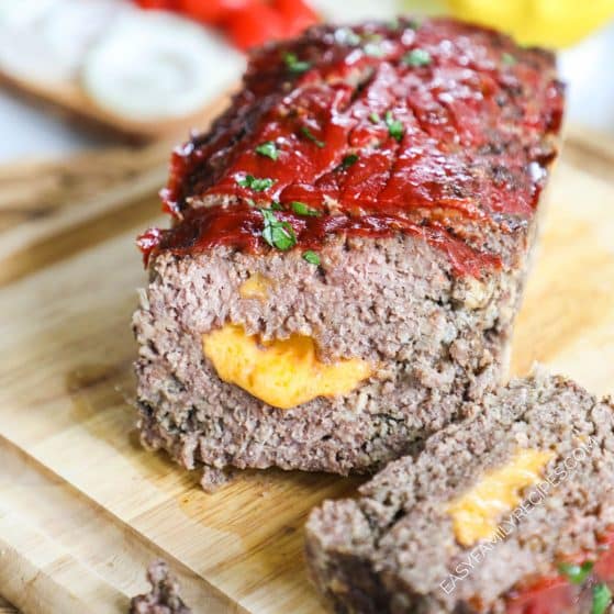 a cheeseburger meatloaf sliced on a cutting board.