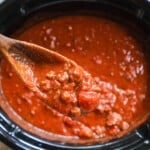 marinara sauce in a large stockpot with a wooden spoon.